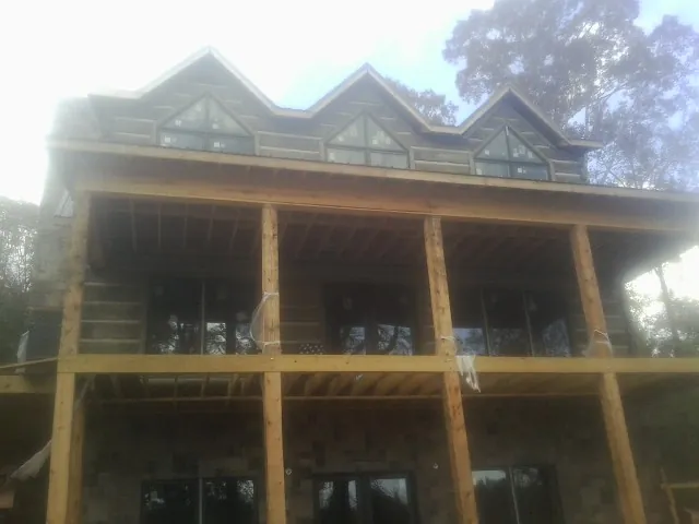 Dormers and porch framing on a large log home under construction — Roof Coating work by our crew in Brunsville