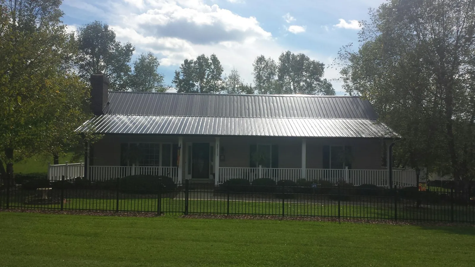 Gray metal roof on a brick ranch with a full width front porch — Gutter Guard Installation work by our crew in Brunsville