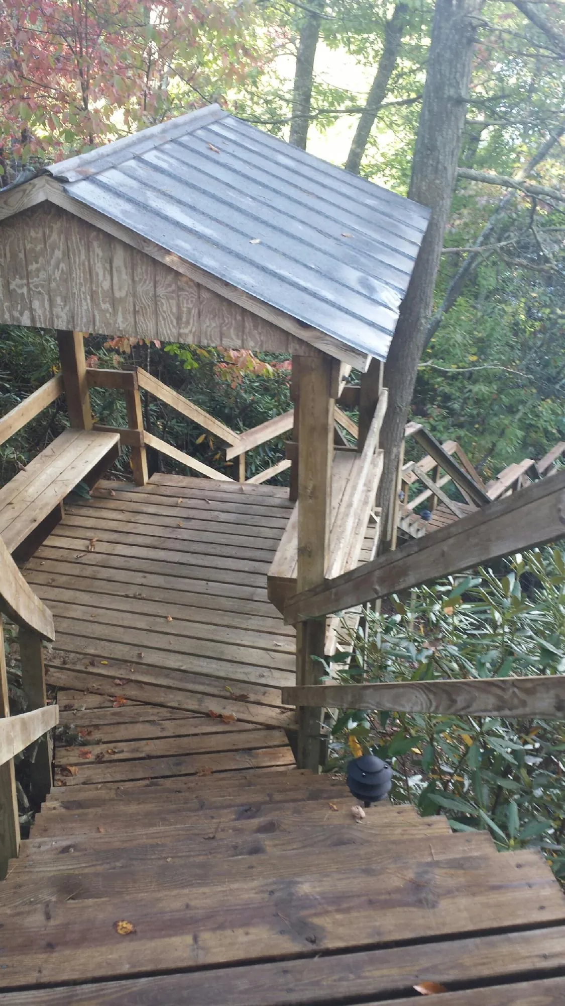 Metal roofed shelter over wooden steps on a wooded walkway — Skylight Repair & Installation work by our crew in Brunsville