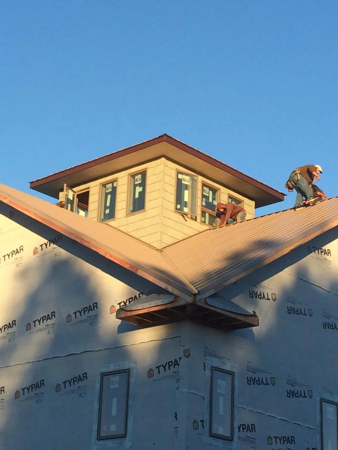 Roofers working around a rooftop cupola on a new metal roof at sunset — Roof Waterproofing in Brunsville by Roofing Brothers